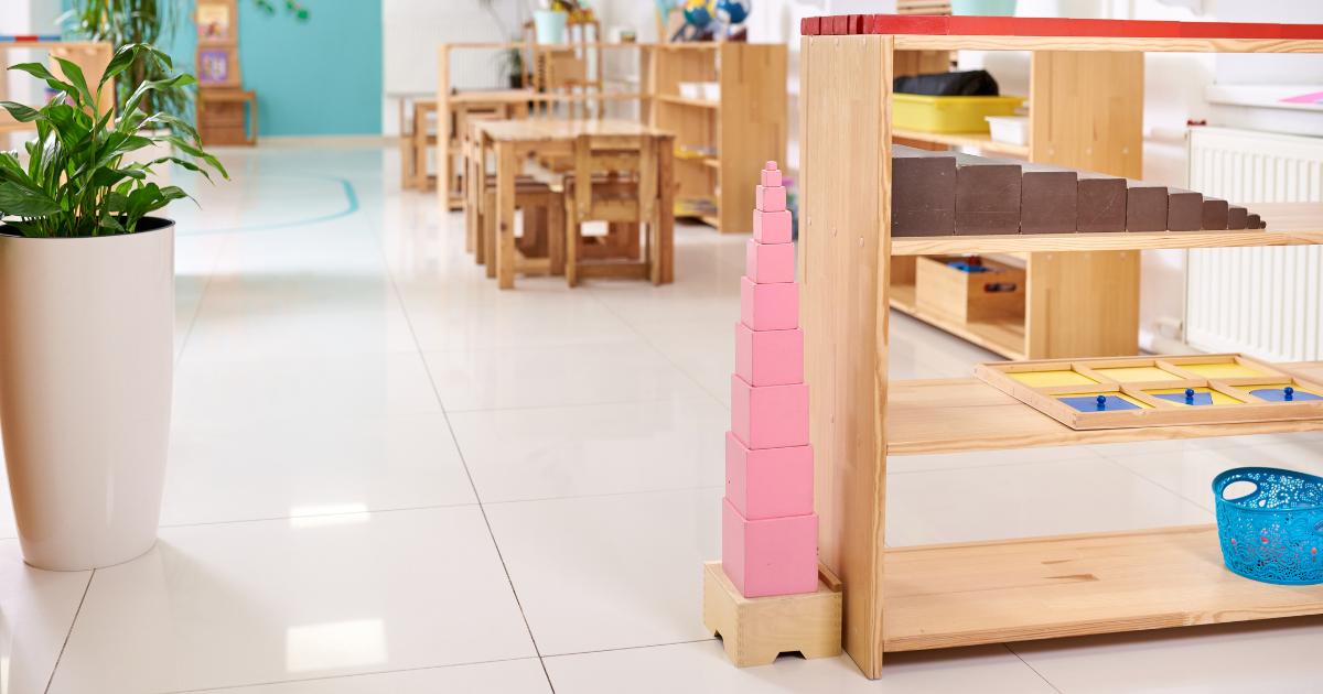 In this episode of Montessori Talks, we discuss the inspiring story of Najee and Sesealy Owens, the new owners of Decatur Montessori School in Atlanta. Image shows a beautiful Montessori classroom with the pink tower as the central focus of the image. The red rods and the brown stair are also visible. There are tables with chairs, plants and shelving in the background.