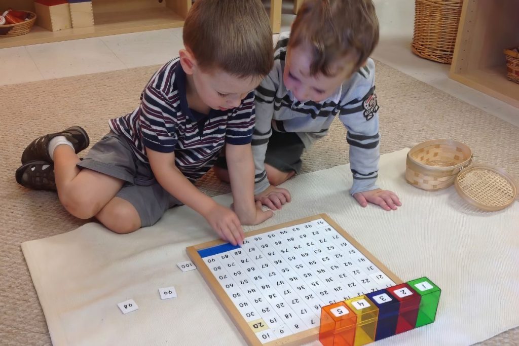 grace and courtesy in Montessori- two children working together on the hundreds board